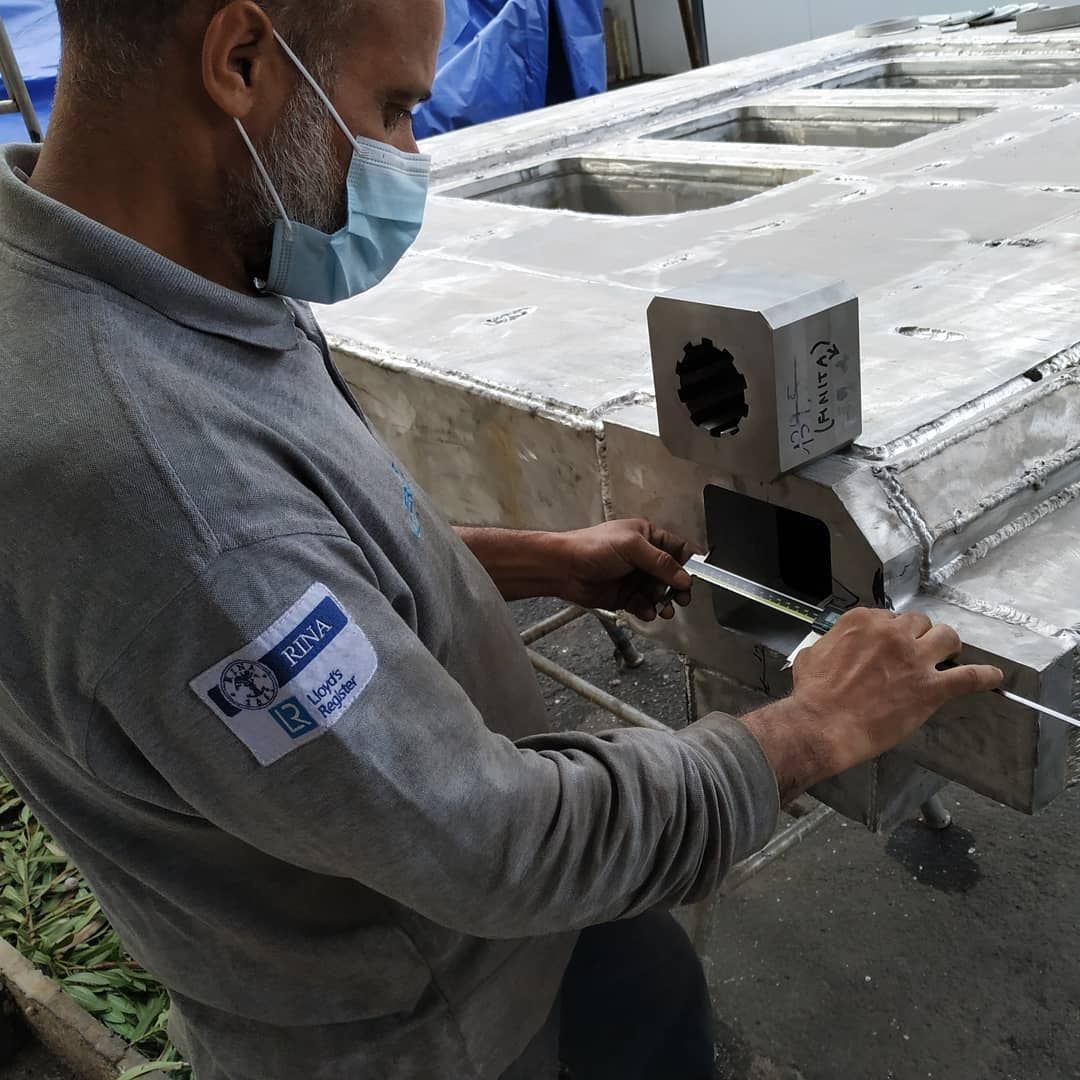 Tecnico che misura con calibro un componente in alluminio saldato