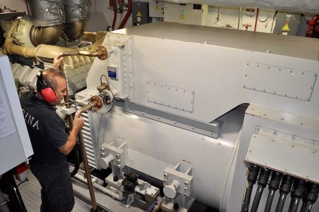 Tecnico al lavoro in sala macchine accanto a un grande generatore