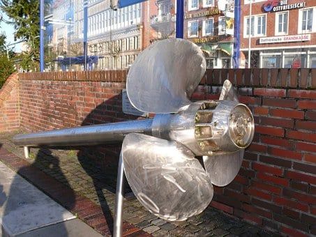 Grande elica in acciaio inox esposta contro un muro di mattoni