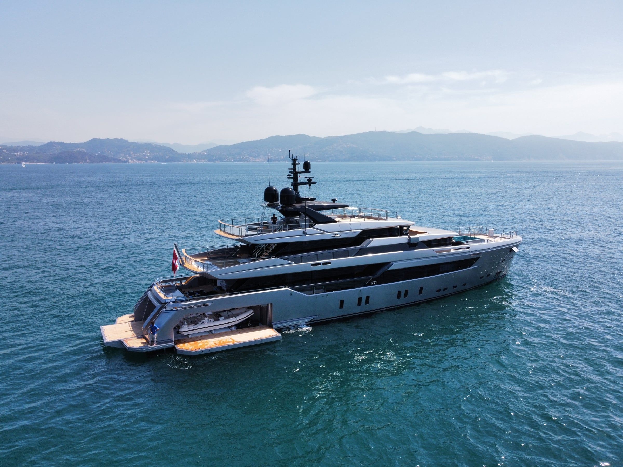 Grey superyacht at sea with open tender garage and aft platform