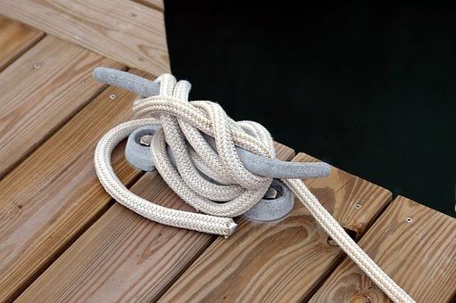 Bitta da ormeggio con cima avvolta su un pontile in legno
