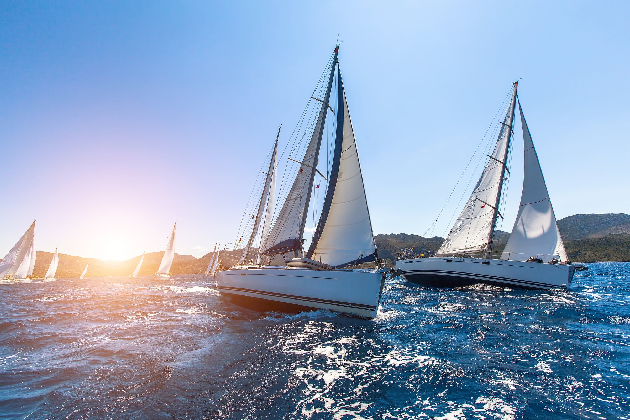 Barche a vela in regata con il sole all'orizzonte